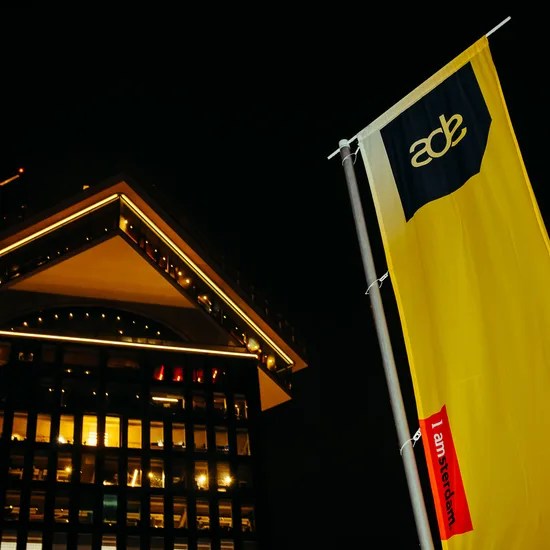 Drapeau jaune de l’Amsterdam Dance Event (ADE) devant un immeuble illuminé à Amsterdam la nuit