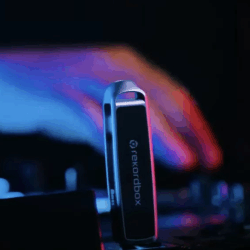 Clé USB Rekordbox SanDisk x AlphaTheta posée sur une platine DJ, avec une main floue en arrière-plan et des lumières bleues et roses