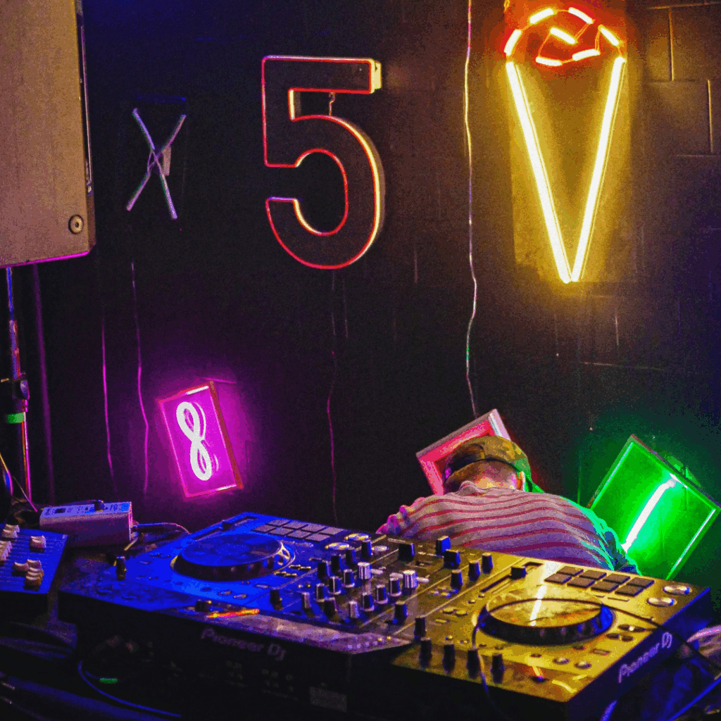 Régie DJ au Paris Audio Video Show avec platines Pioneer devant un mur de néons colorés