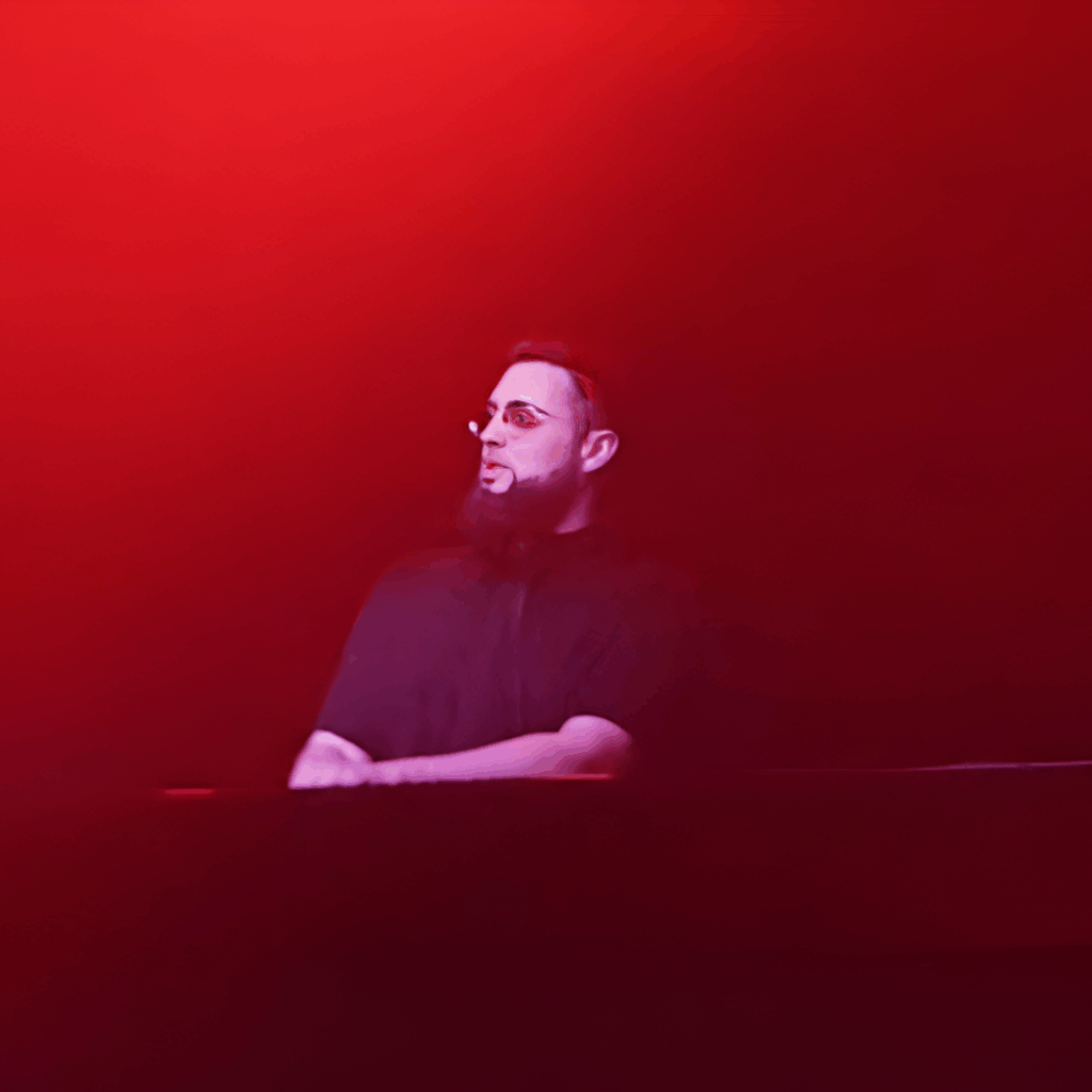 DJ en noir de profil derrière le booth, éclairé par une forte lumière rouge sur scène à l’Audio Club Genève