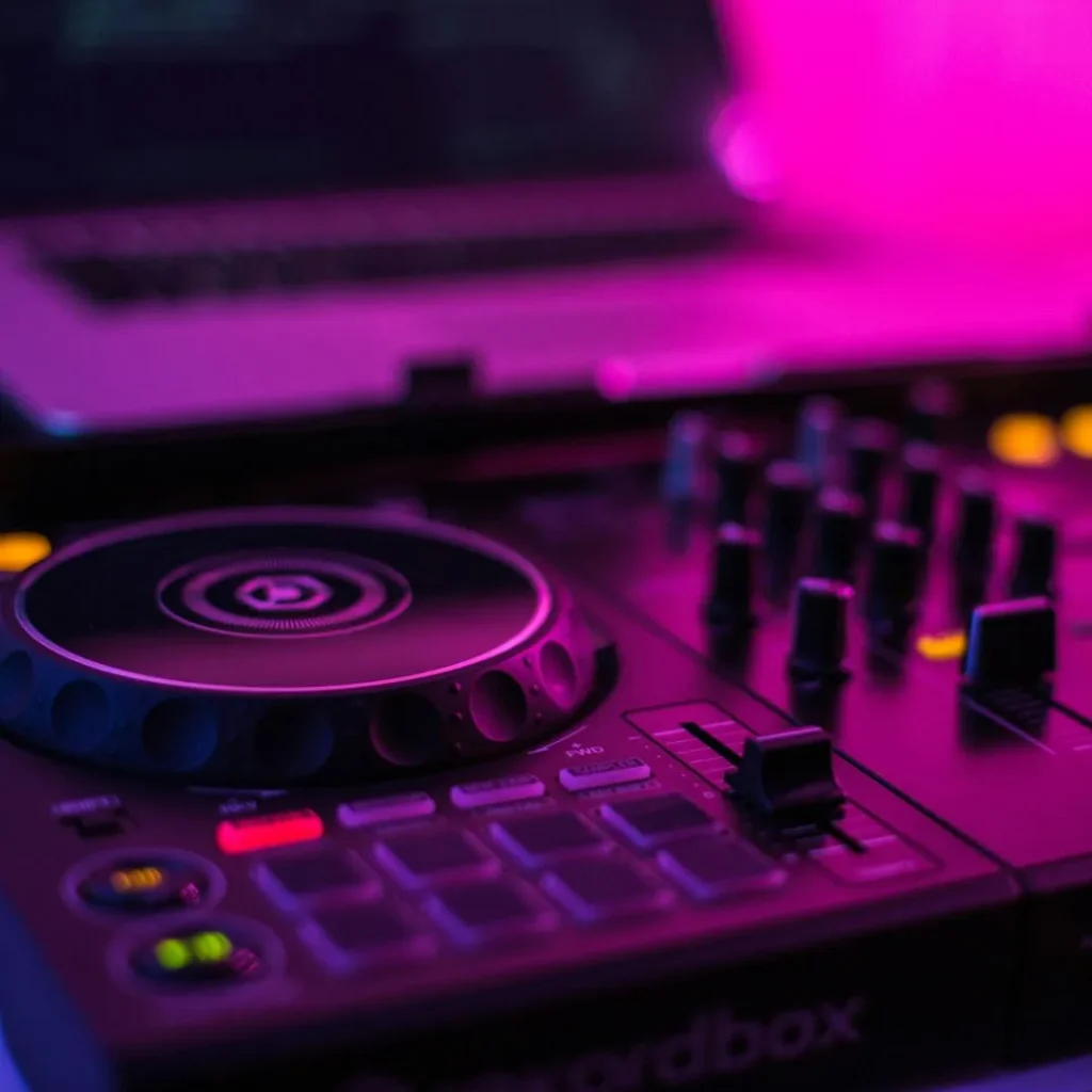 Controleur DJ compact posé devant un ordinateur portable, éclairé par une lumière violette