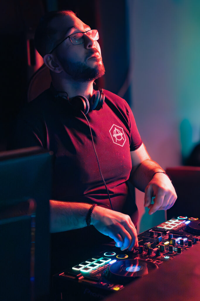 DJ AY3L aux platines pendant une prestation en club, lumière rouge et bleue.