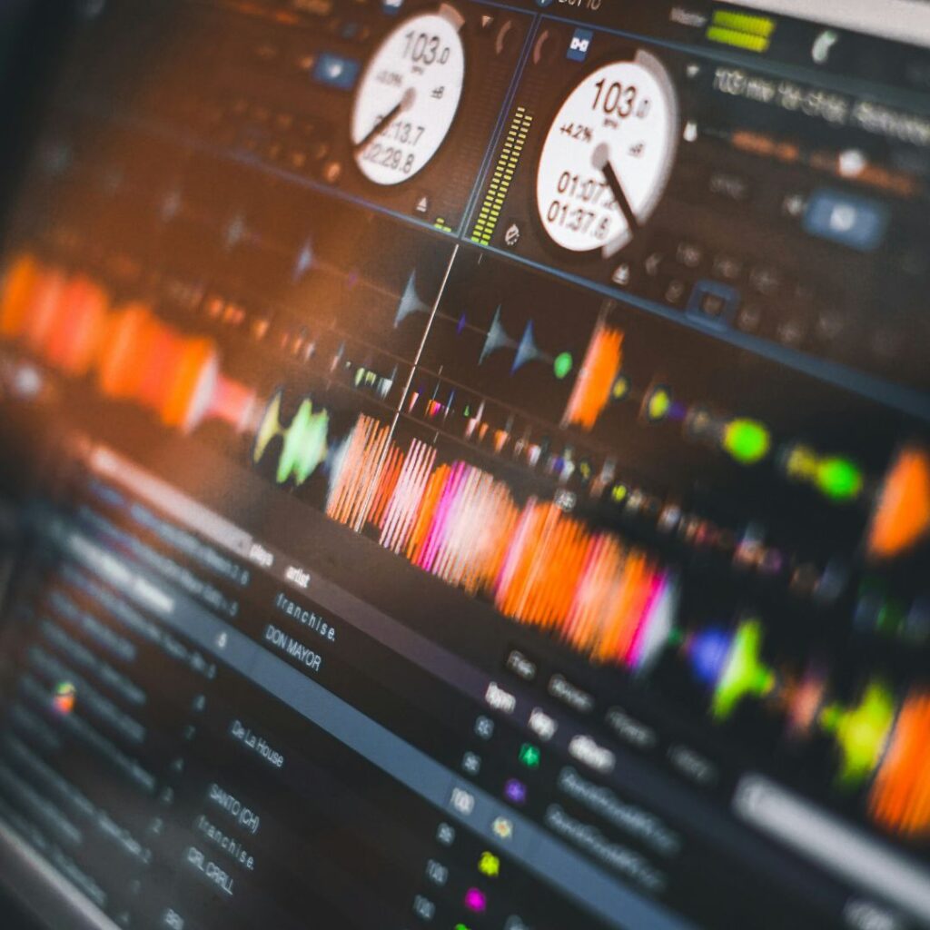 Écran d’ordinateur affichant un logiciel DJ avec formes d’onde colorées et pistes en cours de lecture
